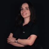 half-picture-of-a-woman-smiling-with-her-arms-crossed-wearing-black-with-black-background